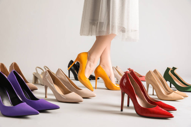 Female legs and many stylish high heels on grey background - Zdjęcie, obraz