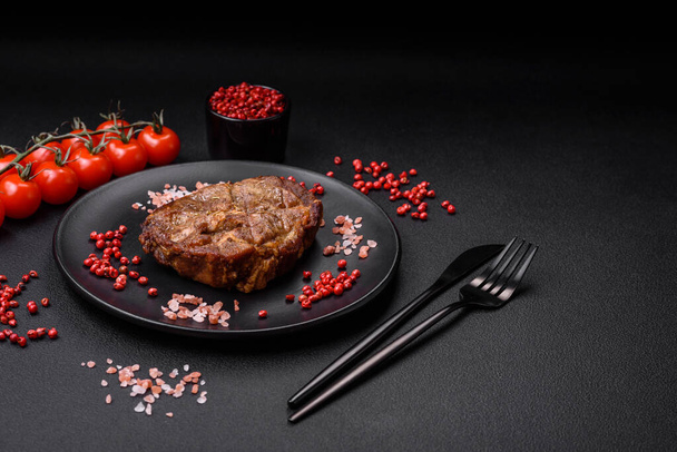 Köstliche saftige Steaks vom Schwein oder Rind gegrillt mit Salz, Gewürzen und Kräutern auf einem strukturierten Betonhintergrund - Foto, Bild