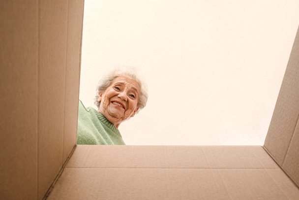 Femme âgée avec colis ouvert, vue de l'intérieur - Photo, image