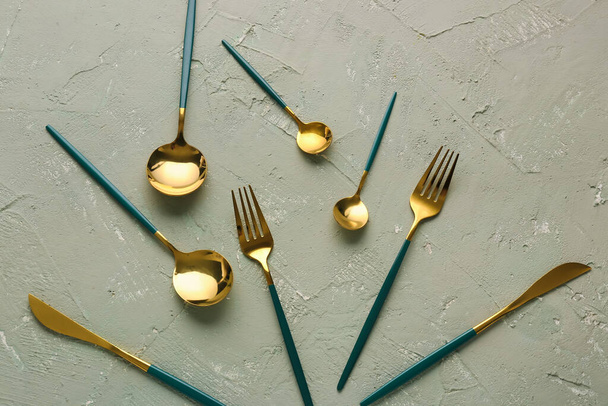 Golden set of cutlery with green handles on grey background - Photo, Image