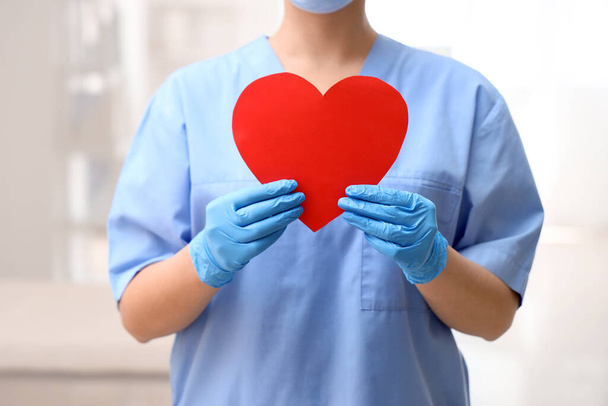 Female nurse with paper heart in clinic, closeup - Photo, image