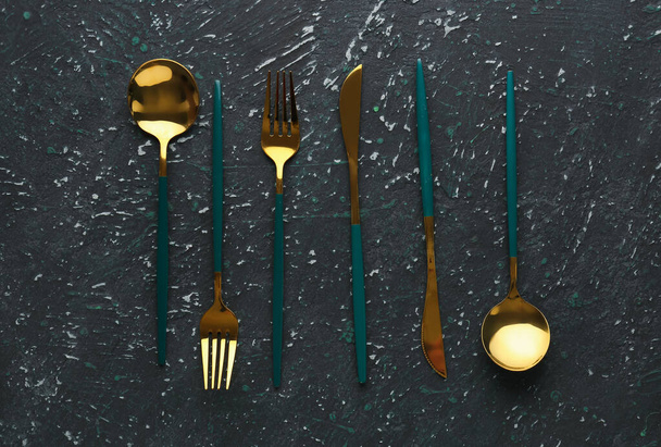 Golden cutlery with green handle on dark grunge background - Photo, Image
