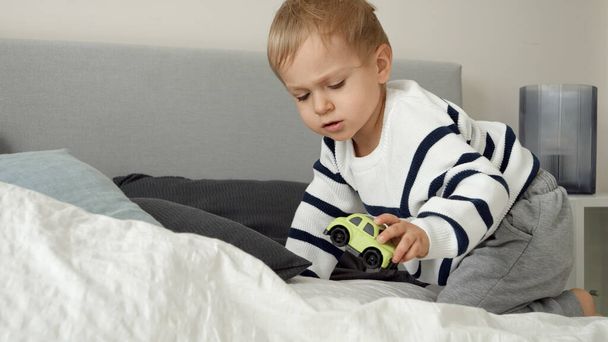 Niedliche Kleinkind Junge krabbeln auf dem Bett mit weichen Kissen und Decke. - Foto, Bild