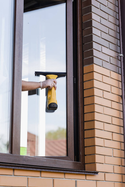 Процесс мытья окон снаружи для удаления пыли, грязи и воды. Очистка окна с помощью портативного пылесоса - Фото, изображение