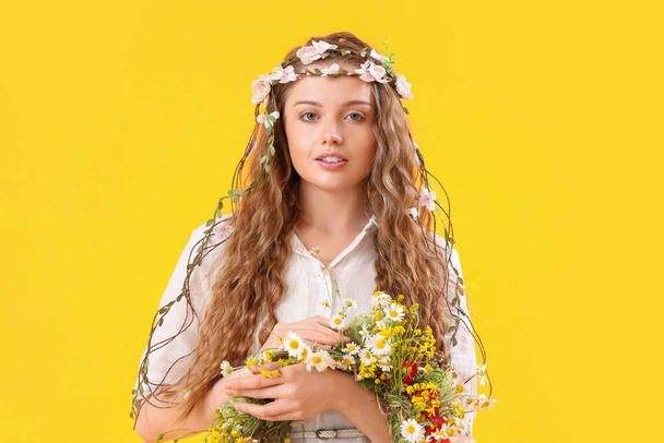 Beautiful young woman with flower wreath on yellow background. Summer solstice - Foto, imagen