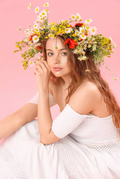 Beautiful young woman in flower wreath on pink background. Summer solstice - Fotó, kép