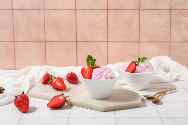 Bowls of strawberry ice cream and spoons on white tile table - Photo, Image