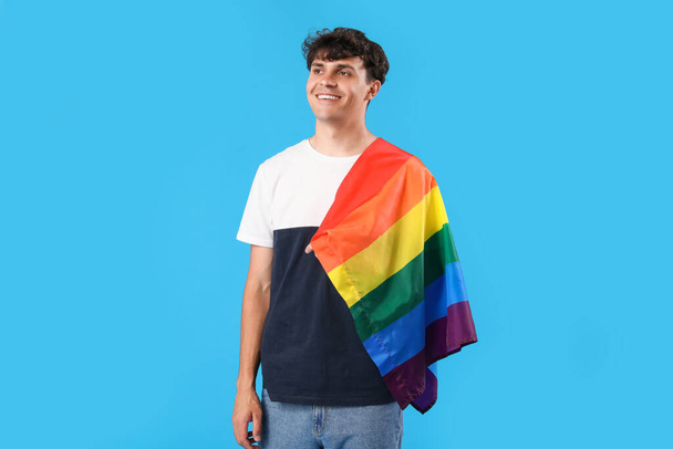 Молодий чоловік з ЛГБТ - прапором на синьому тлі. - Фото, зображення