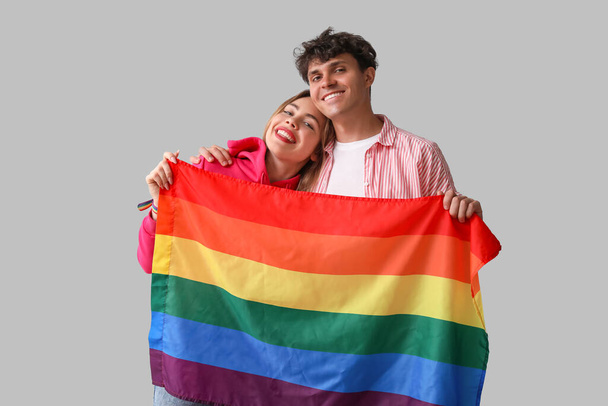 Young couple with LGBT flag on light background - Foto, Imagem