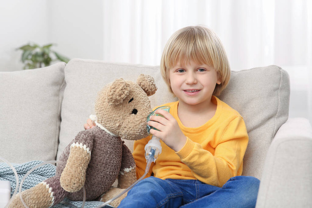 Happy boy with toy bear and nebulizer for inhalation at home - Foto, Bild