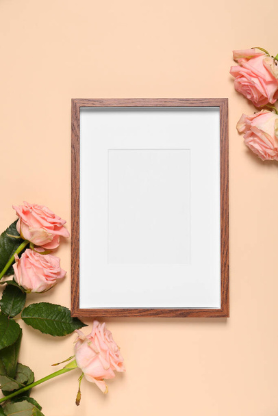 Empty photo frame and beautiful flowers on beige background, flat lay. Space for design - Fotó, kép