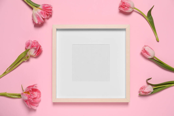 Empty photo frame and beautiful flowers on pink background, flat lay. Space for design - Фото, зображення