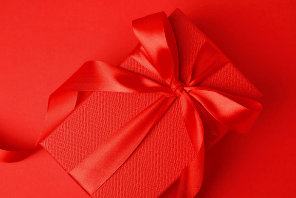 Mooie geschenkdoos met strik op rode achtergrond, bovenaanzicht - Foto, afbeelding