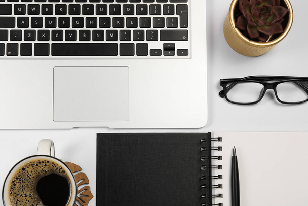 Modern laptop, notebook, pen, houseplant, glasses and cup of coffee on white background, flat lay - Φωτογραφία, εικόνα