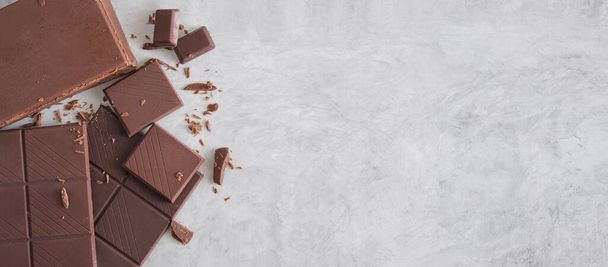 Dark chocolate bar pieces on gray concrete background.  Flat lat, top view with copy space. - Foto, afbeelding