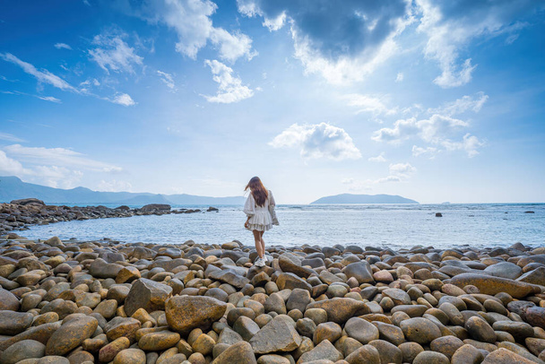 Vacanze estive. Sorridente donne asiatiche rilassanti e in piedi, passeggiando sulla spiaggia Con Dao, così felice e di lusso in estate vacanza, all'aperto cielo cinematografico sfondo. Viaggio e stile di vita Concept. - Foto, immagini