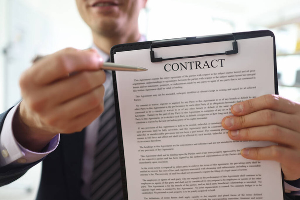 Mosolygós menedzser mutatja szerződést vágólapon partner az irodában. Az üzletember felajánlja, hogy aláírás előtt elolvassa a megállapodás dokumentumait. - Fotó, kép
