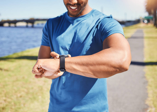 Fitness, exercise and man with a watch outdoor for training or running progress at park. Smartwatch on arm of happy athlete person in nature with time to workout, start run and check performance goal. - Foto, immagini