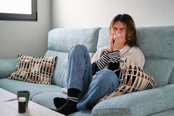 Uomo taiwanese malato che si soffia il naso con un fazzoletto su un divano. Febbre, influenza, concetti di malattia. - Foto, immagini