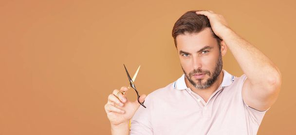 Mens hairstyle, haircut. Millennial man with scissors cut hair. Mens haircare, beauty barber concept. Bearded man, with scissors. Cut hair with scissors. Banner for header, copy space. Poster for web - Photo, image