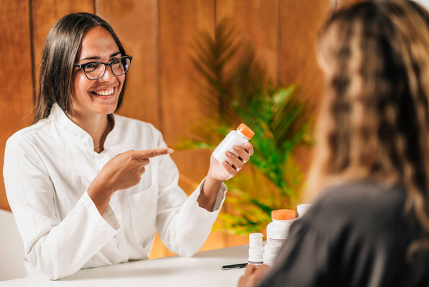 Λειτουργική ιατρική γυναίκα ιατρός συνιστά συμπλήρωμα διατροφής σε έναν πελάτη - Φωτογραφία, εικόνα
