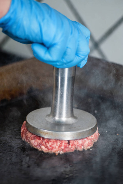 Preparación de hamburguesas en la parrilla con machacadora de hamburguesas - Foto, Imagen