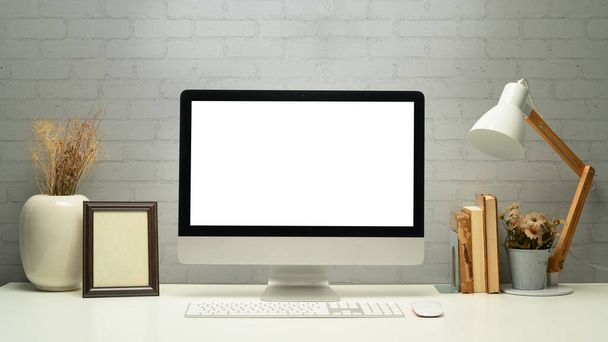 Cómo escritorio de la oficina con la computadora de la pantalla en blanco, marco de imagen y libros. Pantalla vacía para montar su pantalla gráfica. - Foto, imagen