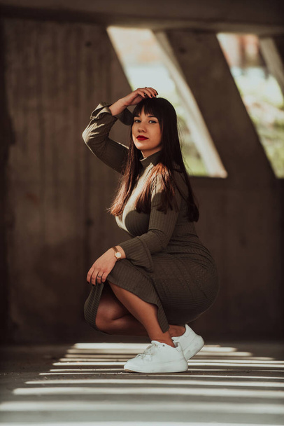 A confident and stylish plus-size woman posing by a modern building in an olive green dress, radiating beauty, empowerment, and self-love - Foto, afbeelding