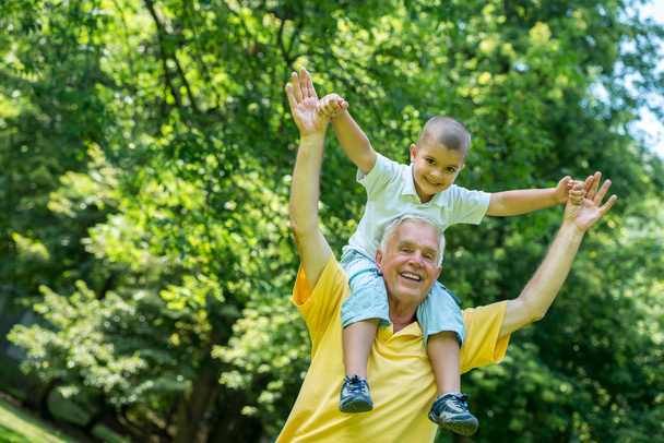 Grandfather and child have fun in park - Фото, зображення