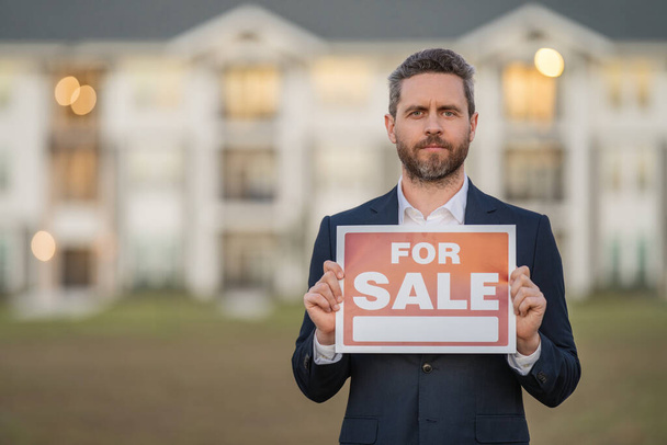 House for sale. Real estate purchase and sale concept. Real estate services. Confident man in suit, real estate agent, professional realtor offering new dwelling real estate house to buyer - 写真・画像