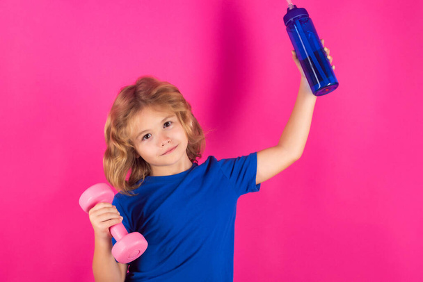 Sportliche Kinder, isoliertes Porträt aus dem Studio auf rosarotem Hintergrund. Kindertraining. Kindersport. Kind turnt mit Kurzhanteln. Sportliches Kind mit Hantel - Foto, Bild