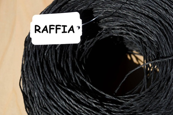 Skein of black raffia on a wooden background. Close-up of raffia. - Photo, Image