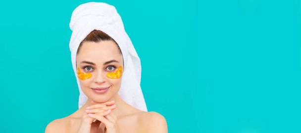 Eye patches, patch under eyes. positive young woman has collagen golden eye patches on face with towel. Beautiful woman isolated face portrait, banner with mock up copy space - Photo, Image