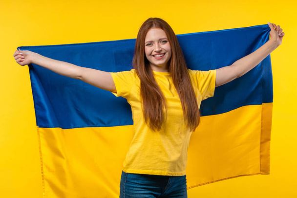 Happy woman with national Ukrainian flag on yellow. Ukraine, patriot, victory in war celebration, banner, Independence day. High quality photo - Photo, Image