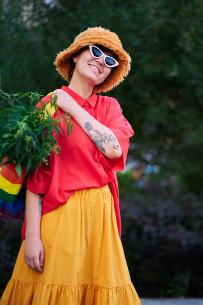 Bright looking female in red t-shirt and yellow skirt with LGBT colors bag full of canabis . High quality photo - Valokuva, kuva