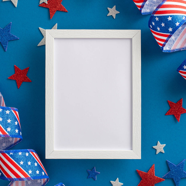 Festive ambiance inspired by USA's Independence Day. Overhead square shot of representative party props, empty photo frame, serpentine and stars, set on blue backdrop with space for text or picture - Photo, Image