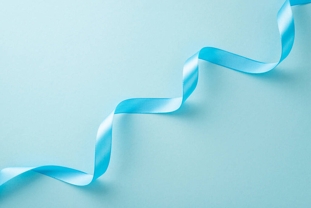 Top view photo of light blue twisted ribbon on a pastel background with copy-space - Fotó, kép