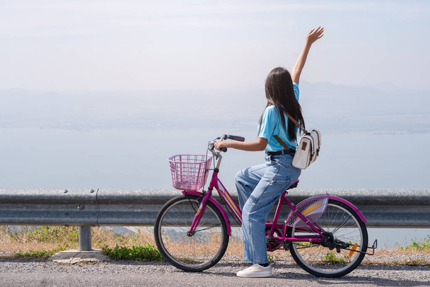 若い女の子は、風力タービン、カオ・ヤイ・テン電気風力タービンタイで山の道に自転車に乗る. - 写真・画像