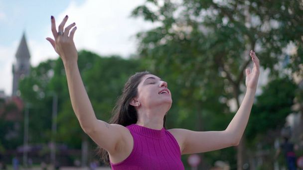 Jedna duchowa młoda kobieta stojąca na zewnątrz, wznosząca ramiona ku niebu, czująca nadzieję i wiarę. Radosna osoba patrząca w górę czująca wdzięczność - Zdjęcie, obraz