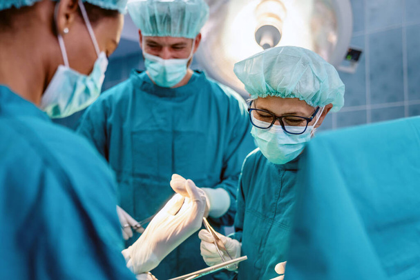 Surgery, medicine and people concept. Group of surgeons at operation in operating room at hospital - Foto, afbeelding