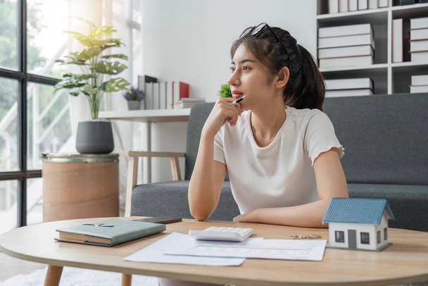 Young woman sit at desk at home manage household finances paying bills calculating on machine calculator. female care of budget use smartphone for payment. Finance concept. - Photo, Image