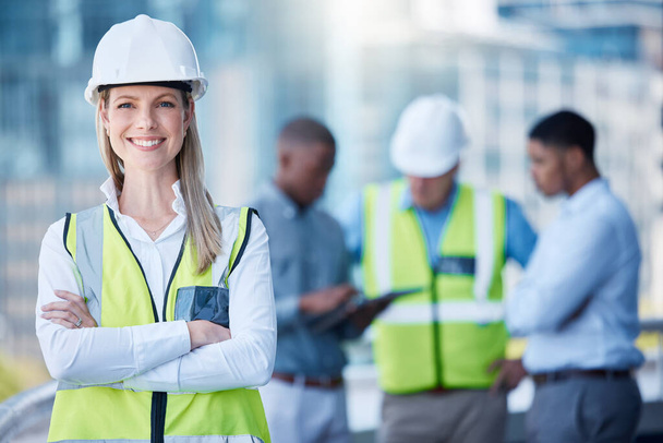 Portrait, arms crossed and a woman construction worker outdoor on a building site with her team in the background. Management, leadership and confidence with a female architect standing outside. - Foto, immagini