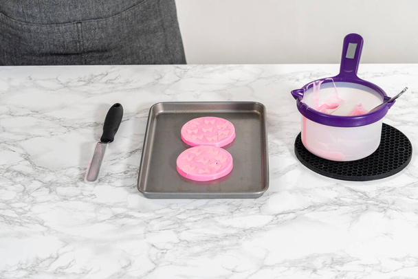 Het bereiden van roze chocoladestrikjes om panda-vormige koekjes te versieren. - Foto, afbeelding