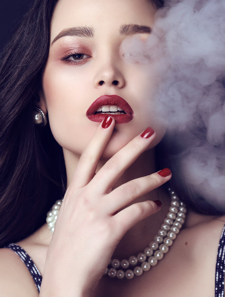 beautiful sensual woman with dark hair and bright makeup with bijou in smoke - Foto, Bild