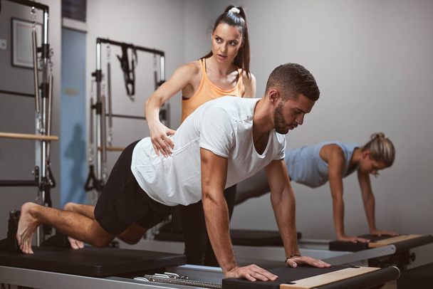 Fiatal nők és férfi testmozgás a tornateremben személyi edző. - Fotó, kép