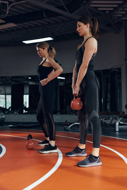 Sporty women doing russian kettlebell exercise in a gym. - Foto, Bild