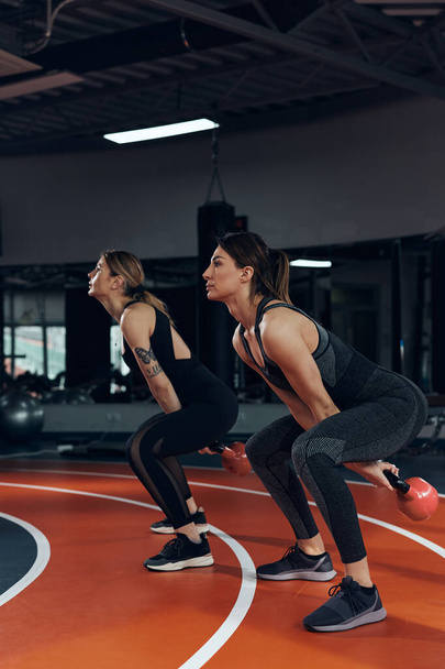 Sportowe kobiety robi rosyjski kettlebell ćwiczenia w siłowni. - Zdjęcie, obraz