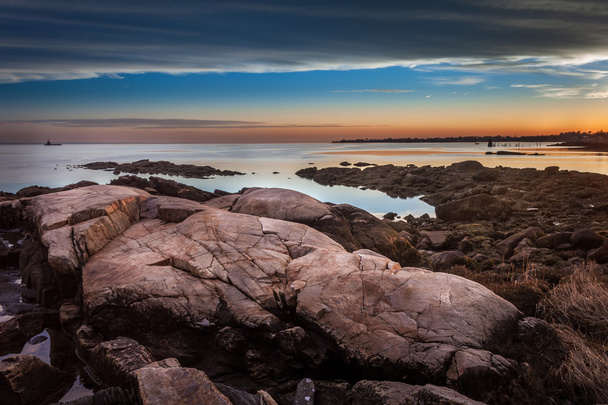 Głazy na brzegu na zachód słońca, Latarnia morska w oddali - Zdjęcie, obraz