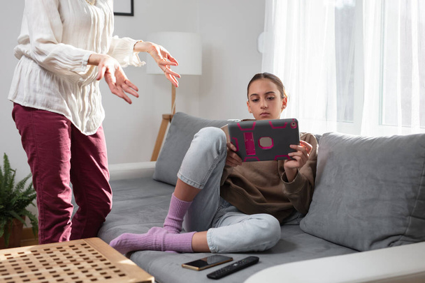 Matka mají potíže s líným teenager dívka doma při hraní videoher na tabletu a smartphonu. - Fotografie, Obrázek