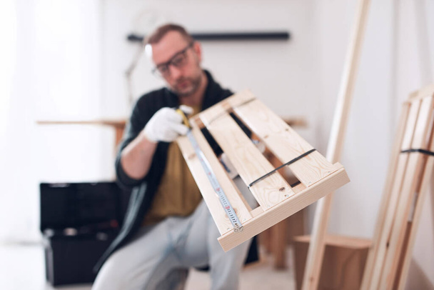 Homem montando nova prateleira de madeira e móveis no apartamento. - Foto, Imagem